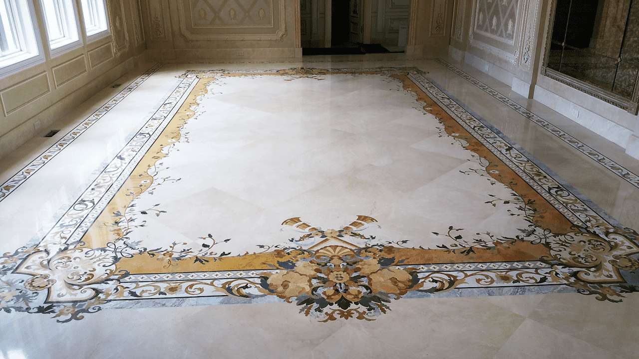 Grand room with a large rectangular marble floor border featuring intricate floral corner patterns. Custom waterjet-cut stone inlays handcrafted in the USA by Czar Floors.